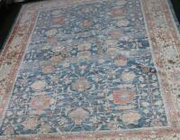 An Eastern bordered carpet with traditional stylized foliate designs in coral and blue on a beige gr