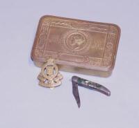 A WWI Princess Mary brass gift tin with a regimental cap badge