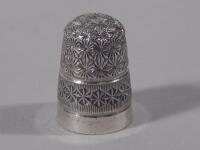 An Edwardian silver thimble decorated with stylised flower heads etc.