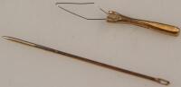 A 9ct gold needle threader and a yellow metal needle