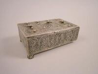 A rectangular white metal filigree cigarette box