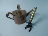 A brass and iron microscope and a copper watering can