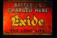 A rectangular tin advertising sign 'Batteries Charged Here Exide for Long Life'