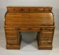 A reproduction stained pine roll top desk