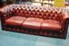 A red leather Chesterfield style three seater buttonback sofa.