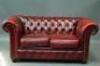 A red leather Chesterfield style two seater sofa