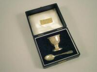 A silver egg cup and matching spoon