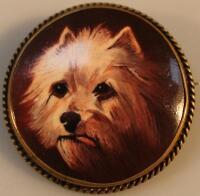 A circular porcelain brooch painted by James Edwin Dean