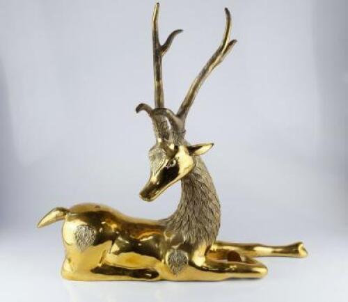 A modern brass figure of a reclining deer