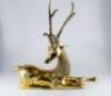 A modern brass figure of a reclining deer