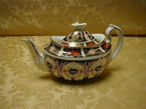 A tea pot, of oval form, the domed cover with conforming finial, scroll