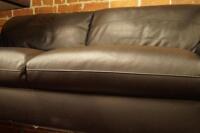 A black leather three seater sofa.