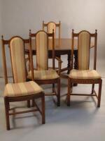 A modern Ercol mid elm coloured extending dining table and four chairs.