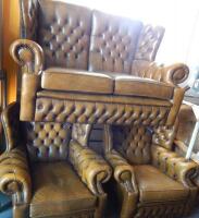 A brown leather wingback three piece suite