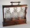 An Edwardian oak three bottle tantalus