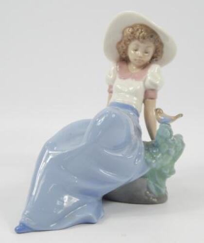 A Nao figure of young lady with a small bird