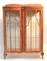 A walnut double bowfronted display cabinet