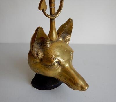 A brass foxes head door porter with riding crop handle