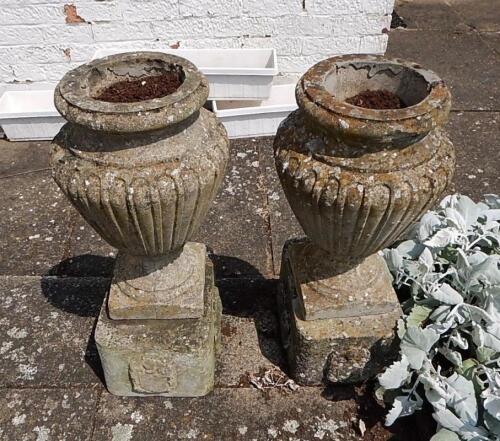 A pair of reconstituted stone urn shaped garden vases