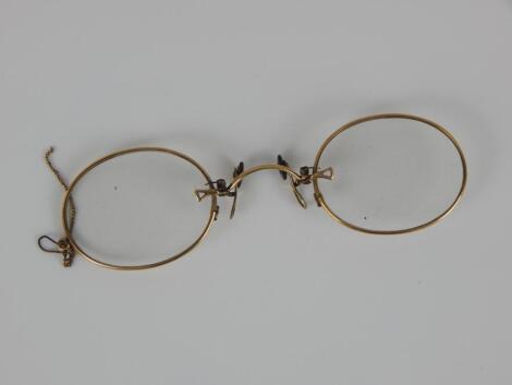 A pair of yellow metal framed spectacles in a case