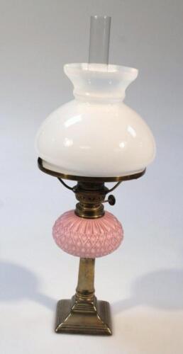 An early 20thC brass and pink glass oil lamp