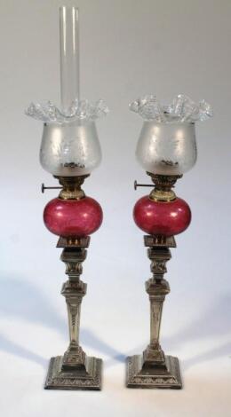 A pair of Mappin Brothers cranberry tinted and silver plated oil lamps