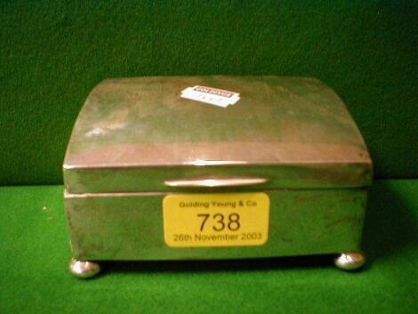 An engine turned silver cigarette box with dome top and ball feet