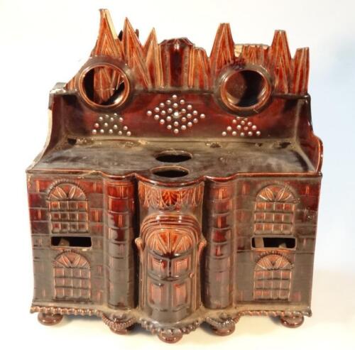 A 19thC treacle glazed pottery watch stand model of a house