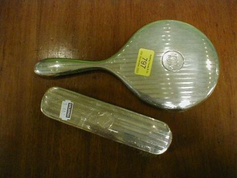 A silver backed hand mirror and matching clothes brush