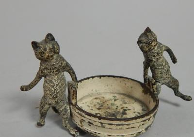 A 20thC cold painted bronze model of two cats holding a coopered bowl