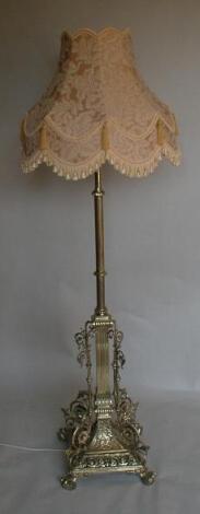 A cast brass standard lamp with reeded column and cast foliate scrolling base on paw feet