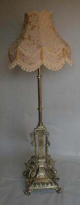 A cast brass standard lamp with reeded column and cast foliate scrolling base on paw feet