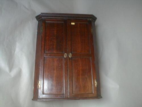 A George III oak hanging corner cupboard with dentil moulded cornice and