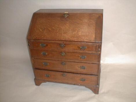 A George III oak bureau with fall flap revealing a fitted interior on lopers