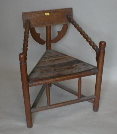 A 19thC oak corner chair of triangular form with carved and bobbin turned framing