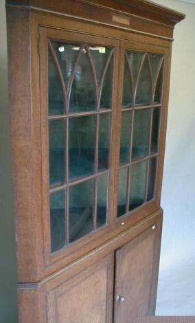 A George III oak corner cabinet with moulded cornice over two astragal