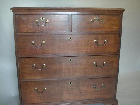 A George III oak chest of two short and three long graduated drawers with