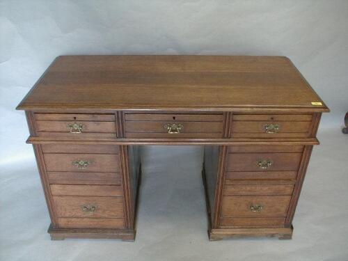 A late Victorian oak kneehole desk with three frieze drawers and two to