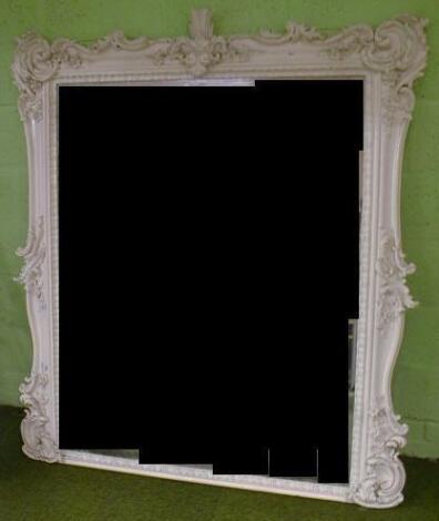 A 19thC rococo wall mirror with a heavy foliate scrolling white painted