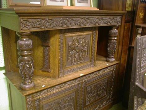 A Jacobean style carved oak court cupboard with arabesque lined fret frieze