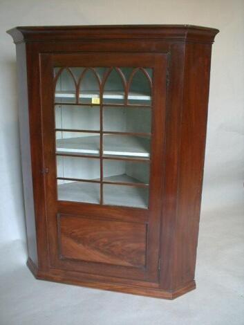 A George III mahogany hanging corner cabinet with moulded cornice