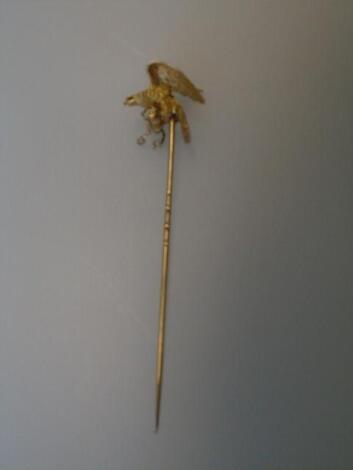 A stick pin surmounted by a golden eagle with ruby set eyes