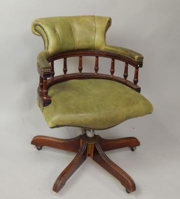 A reproduction green leather desk chair.