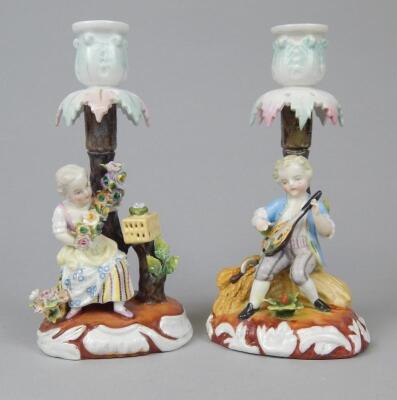 A pair of late 19thC Continental porcelain figural candlesticks