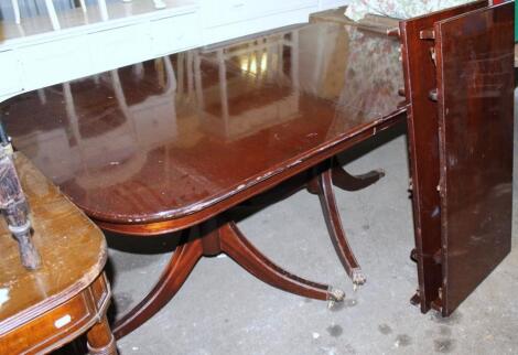 A Regency style mahogany finish extending D-end dining table