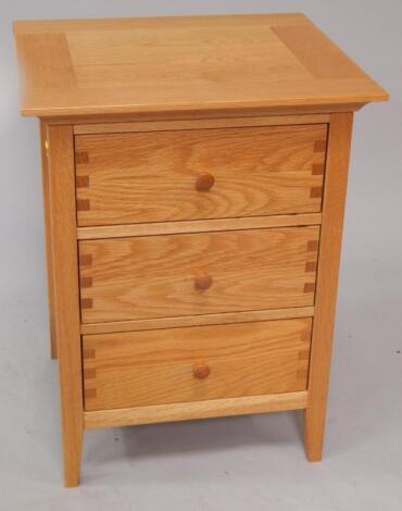 A modern light oak three drawer bedside pedestal.