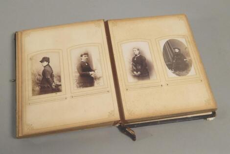 A Victorian leather and brass photograph album containing a number of black and white portraits