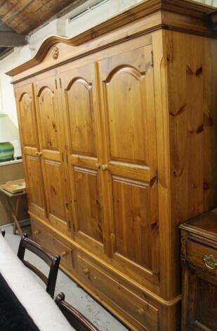 A modern stripped and lightly polished pine triple door wardrobe