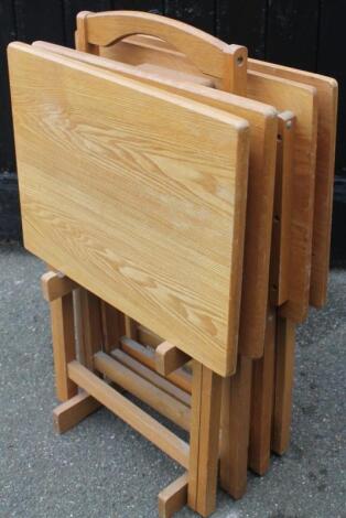 A set of four modern light oak finish folding tables