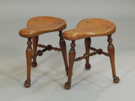 A pair of Victorian walnut saddle shaped stools